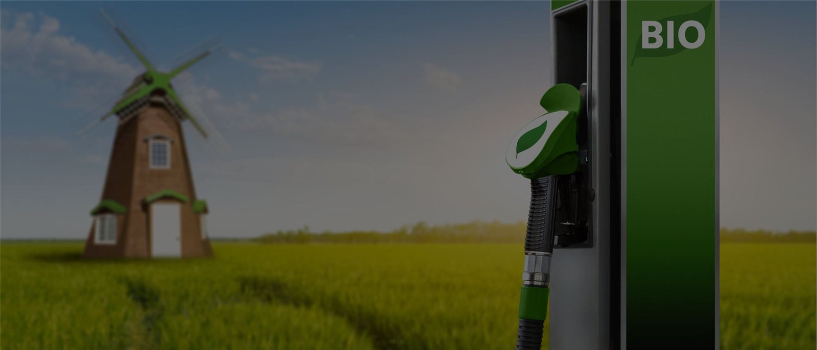 A green biofuel pump with a windmill in a field behind it